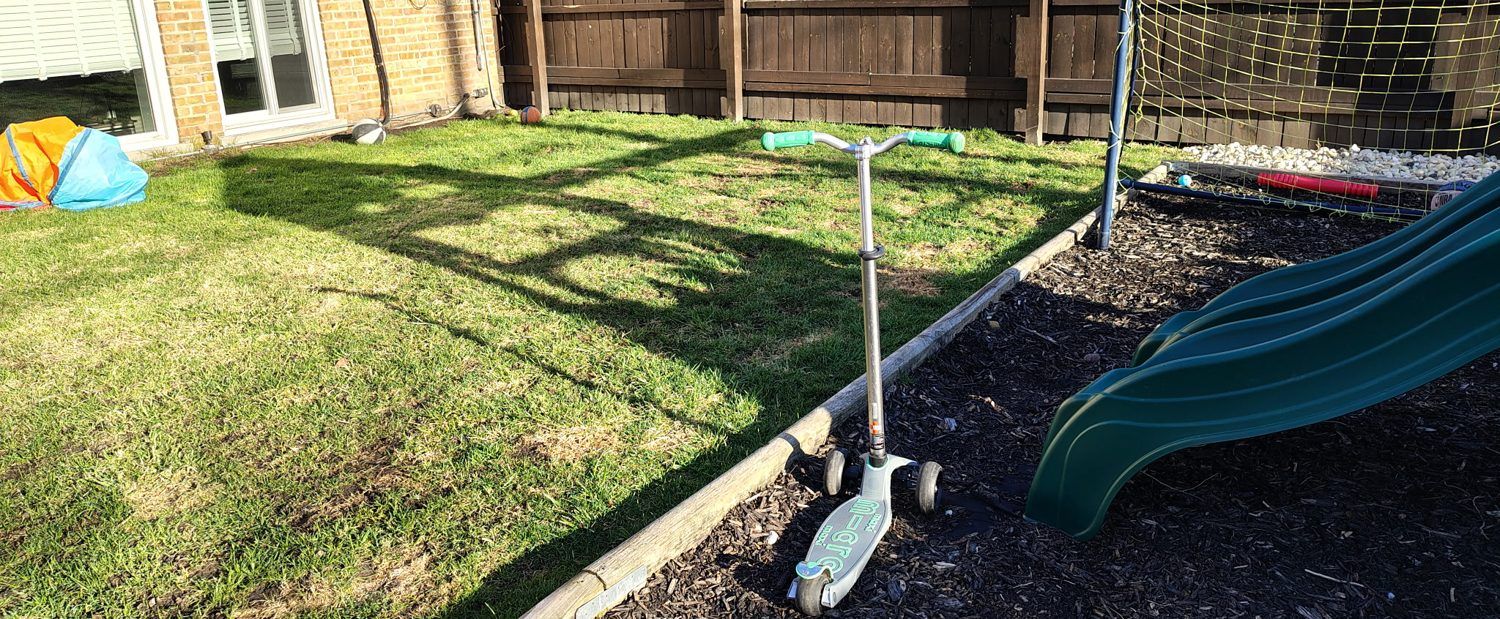 A cleaned back yard with a slide, a scooter and a soccer net