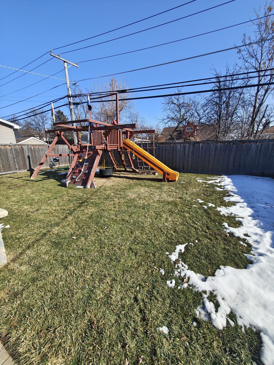 A cleaned lawn with a wooden playset in early spring