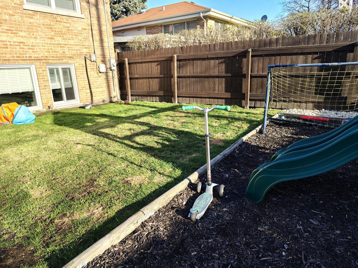A cleaned back yard with a slide, a scooter and a soccer net