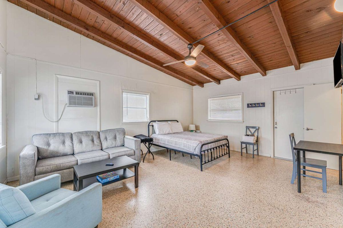 A studio cabin with a bed, a sofa and a wood ceiling