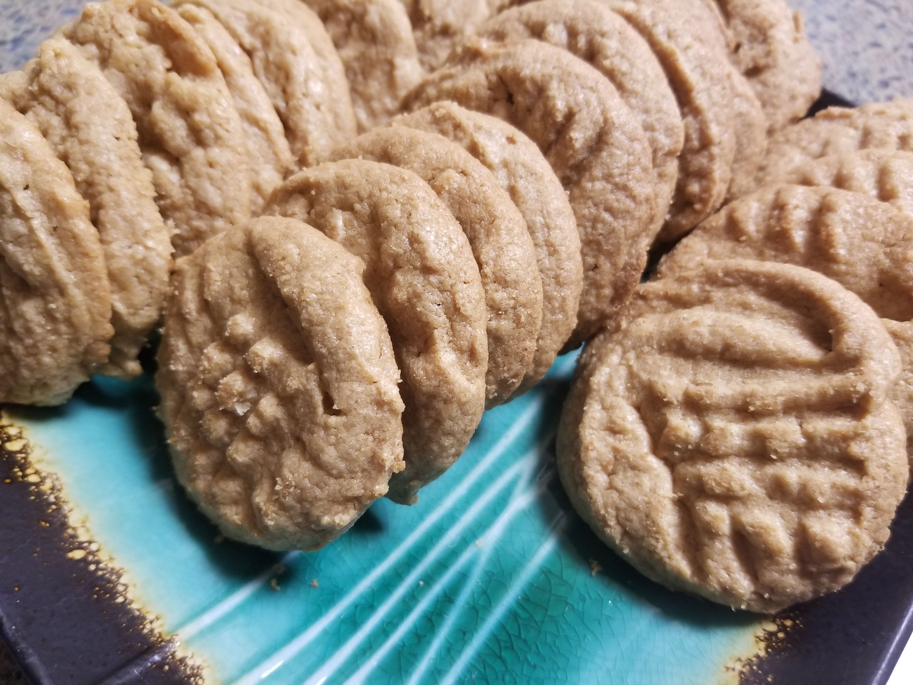 Light brown round cookies with ridged patterns arranged on a blue and white striped plate